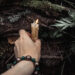 Fotka v lese a záběr na ruku a svíčku mezi dřevem a mechem