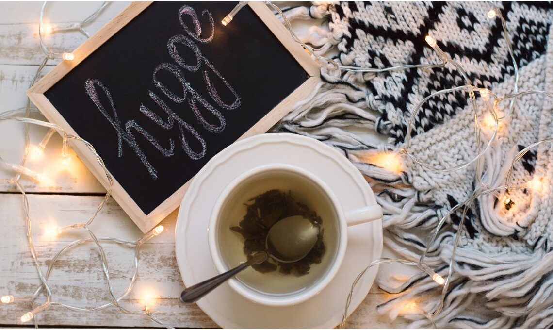 hygge atmosféra pro výklad na sebe-lásku, na stole jsou světýlka, sypaný čaj a příjemná deka